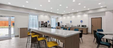 A modern kitchen with a central island, bar stools, and a dining area with chairs.