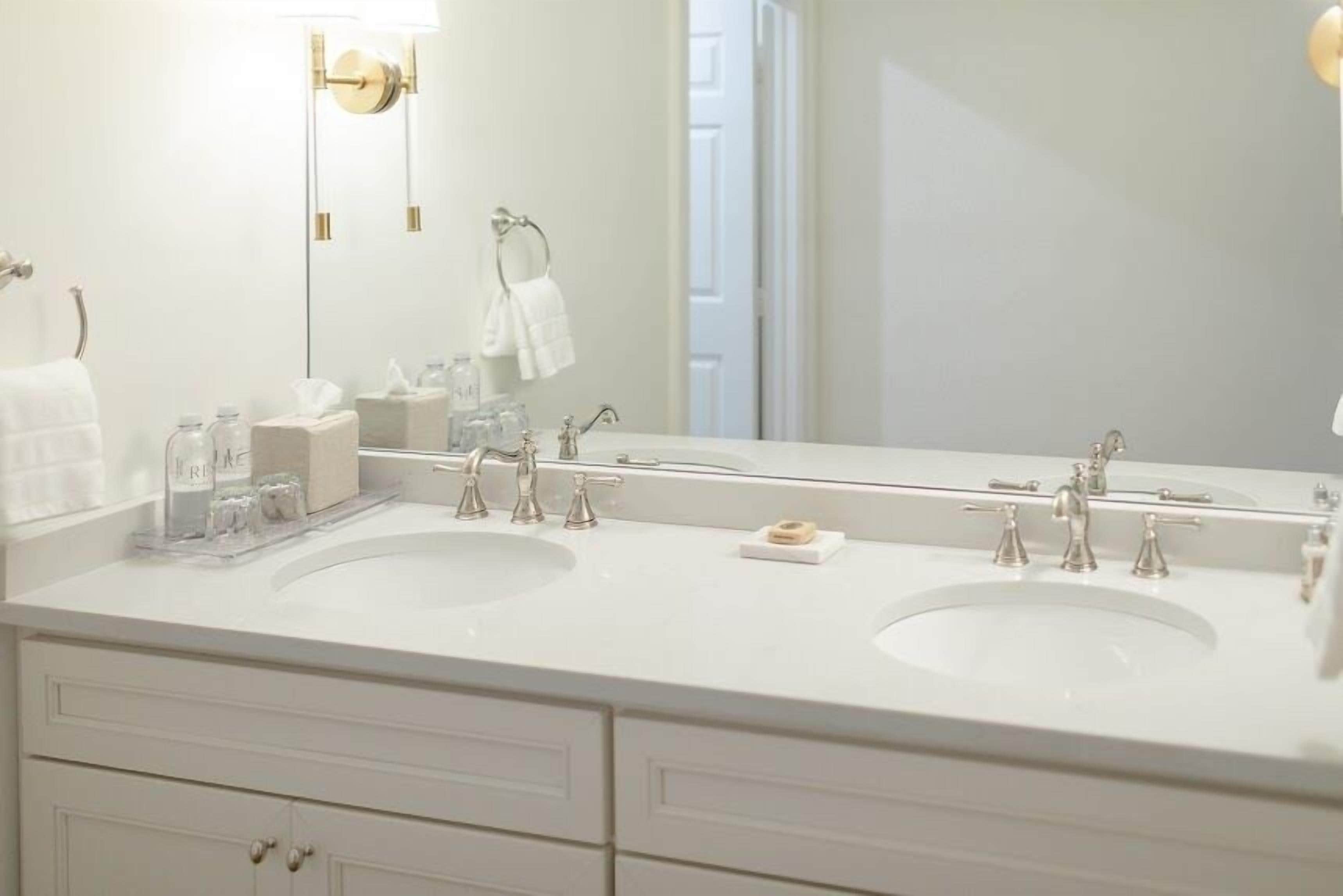 A modern bathroom with two sinks, a large mirror, and a towel rack.
