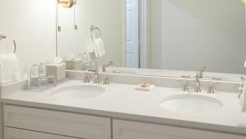 A modern bathroom with two sinks, a large mirror, and a towel rack.