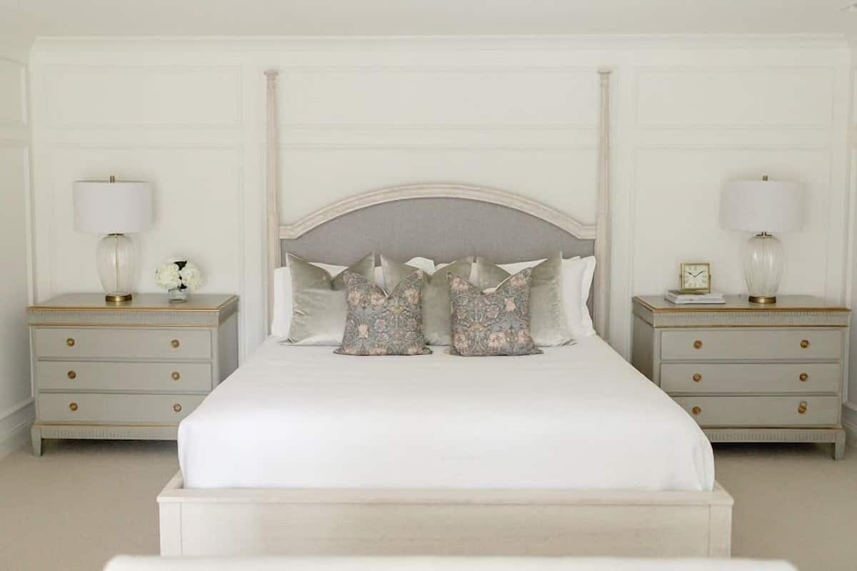 A bedroom with a large bed, two nightstands, and a headboard with decorative pillows.