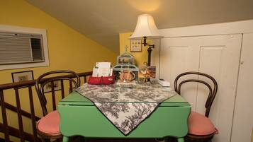 A dining table with a green tablecloth, two chairs, a lamp, and a decorative item on the table.