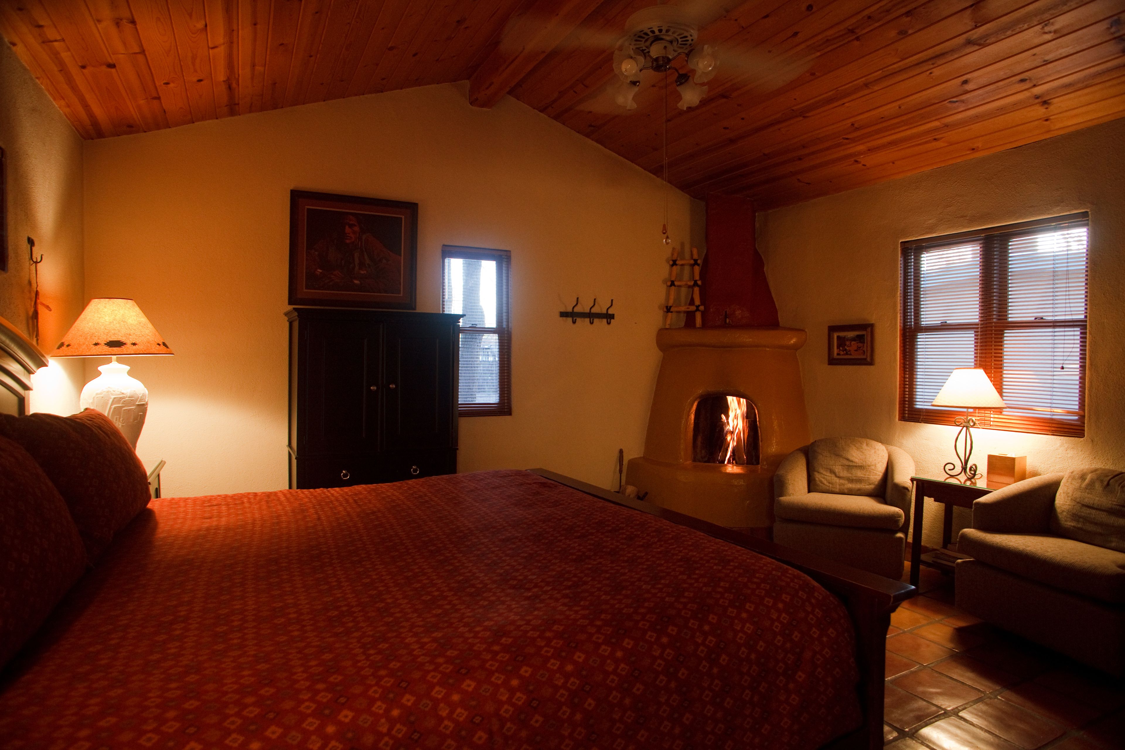 A cozy room with a bed, a fireplace, a chair, and a table.