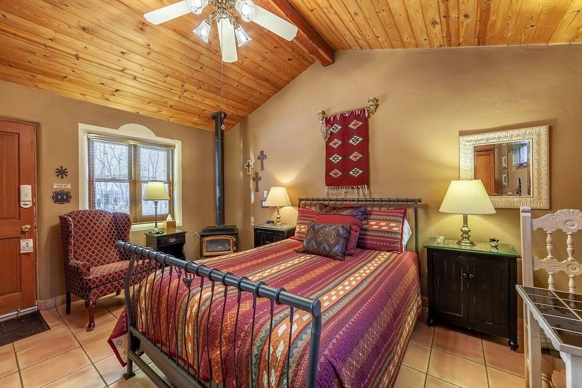 A cozy bedroom with a bed, a chair, a heater, and a window.