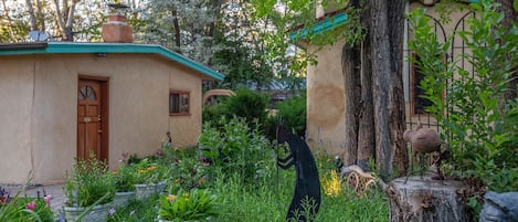Een rustiek huis met een groen dak, omgeven door weelderig groen en een tuin.