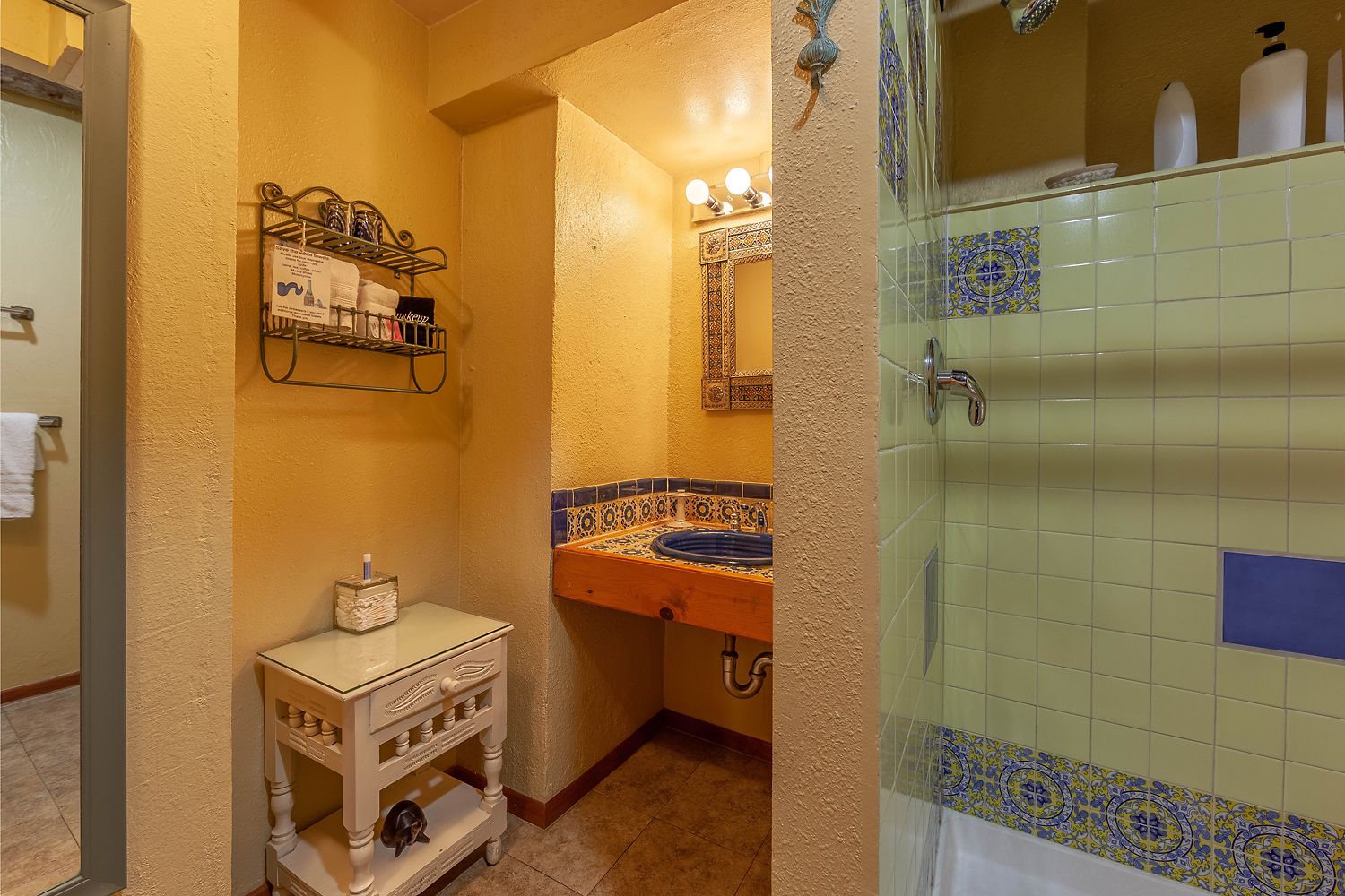 A bathroom with a tiled shower, a sink with a decorative tile backsplash, a towel rack, and a small cabinet.