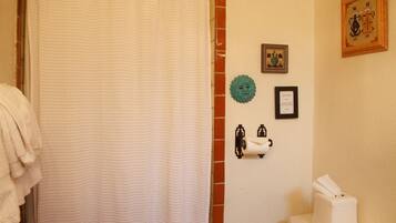 A bathroom with a toilet, a shower curtain, a towel rack, a toilet paper holder, and a framed picture on the wall.