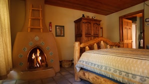 Een rustieke kamer met een stenen openhaard, een houten bed en een houten kast.