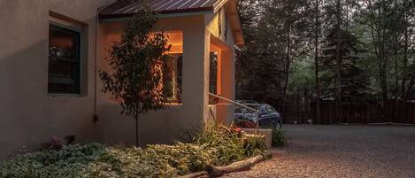 A house with a small porch, a tree, and a gravel driveway.