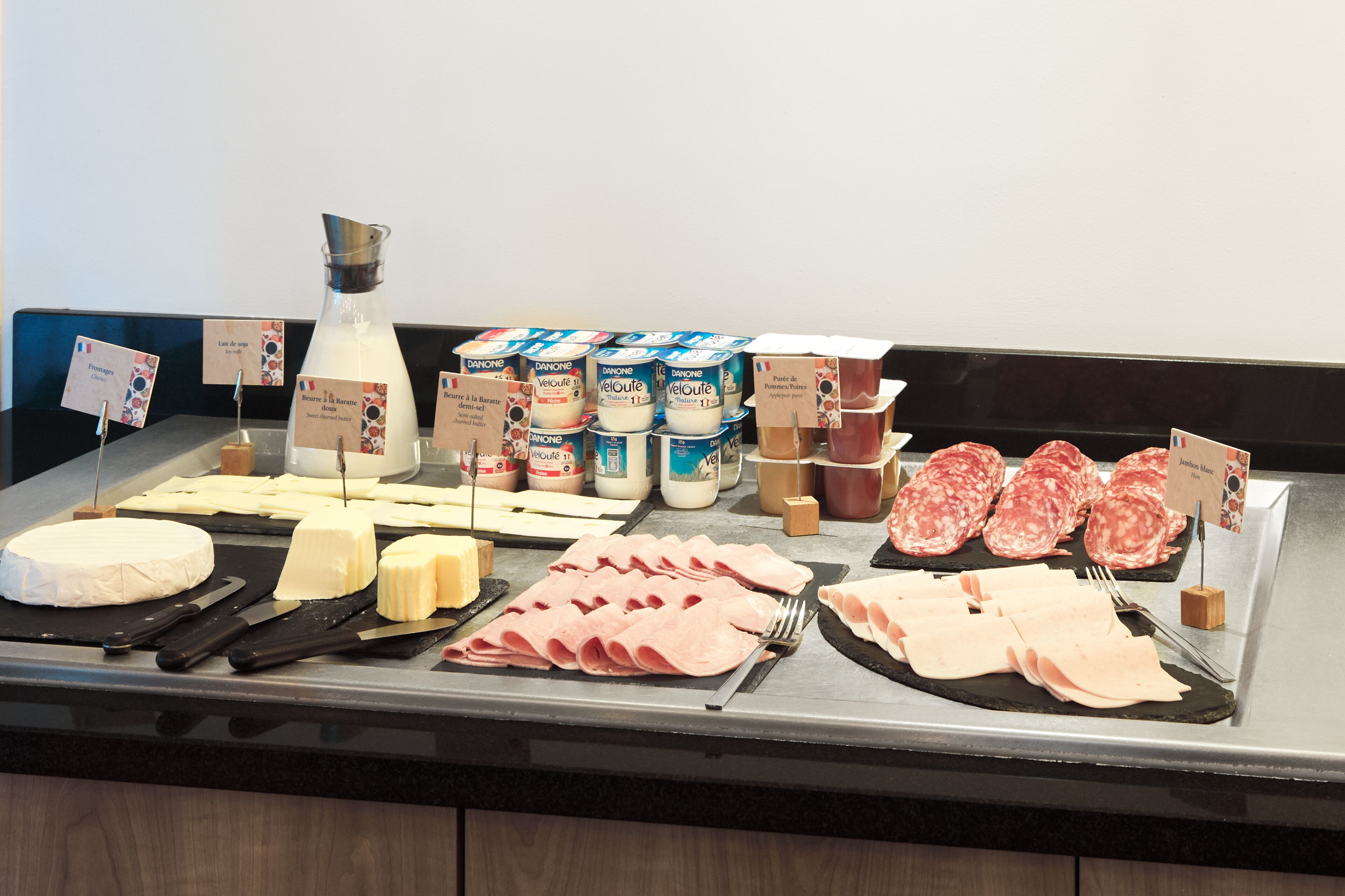 A cheese and deli counter with various cheeses, meats, and dairy products.