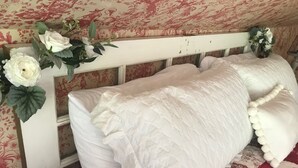 A bed with white bedding and a floral arrangement on the headboard. - Wild Wisteria (Chadds Ford)