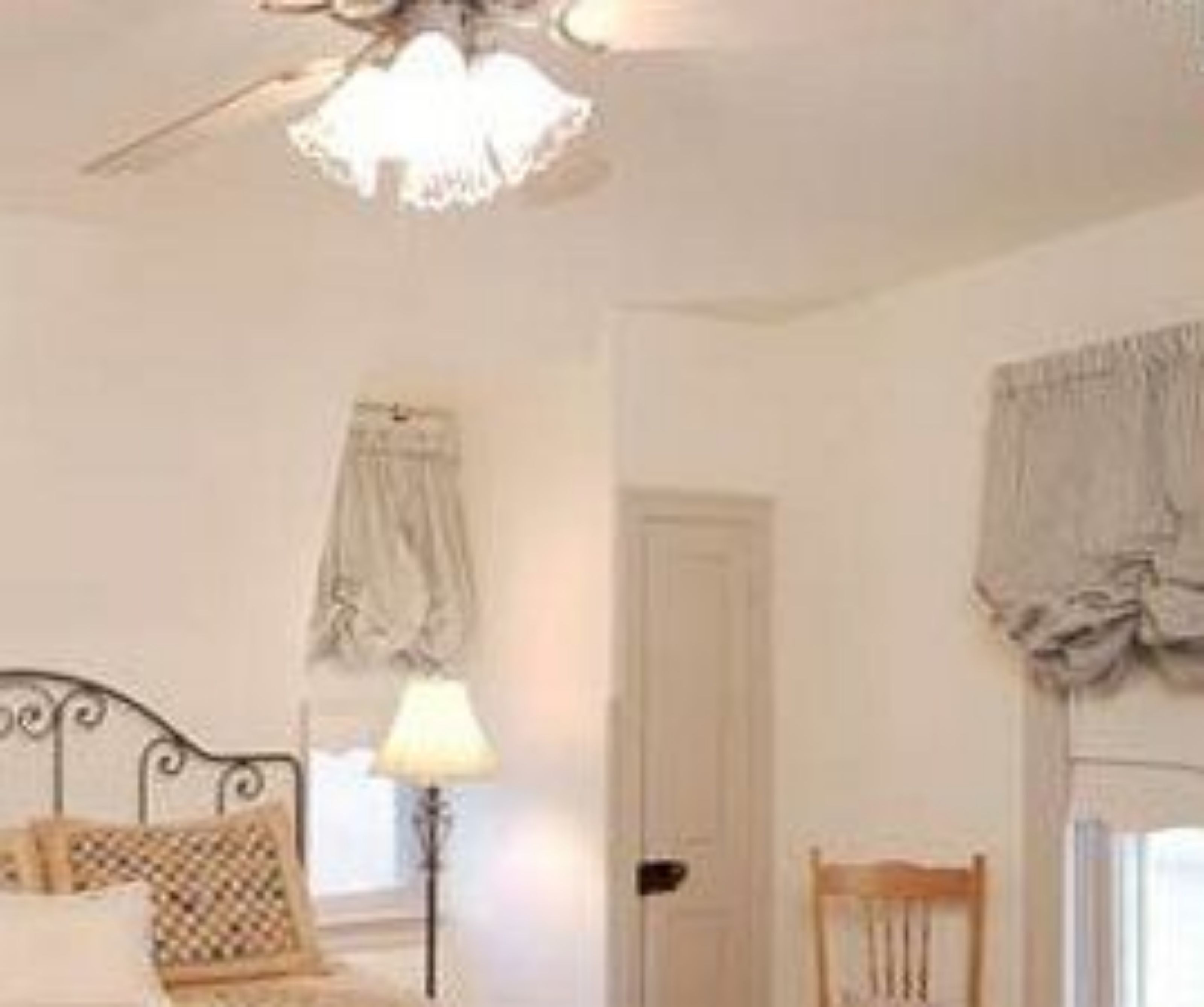 Una habitación con una cama, una lámpara, una silla y una puerta.