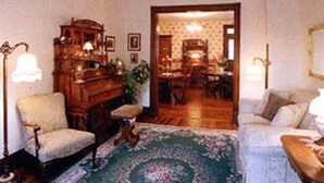 A cozy living room with a piano, a sofa, and a dining area visible through an open doorway.