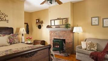 A cozy room with a bed, a fireplace, a sofa, and a wall-mounted clock.