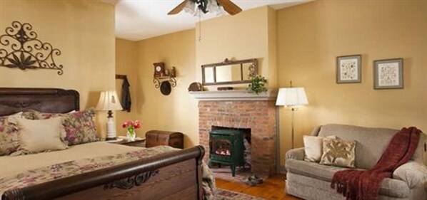 A cozy room with a bed, a fireplace, a sofa, and a wall-mounted clock.