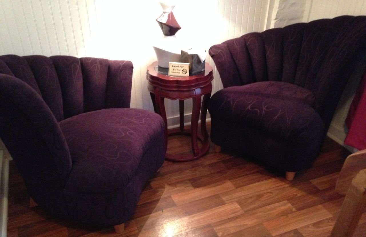 Zwei violette Sessel stehen sich gegenüber, dazwischen ein kleiner Holztisch.