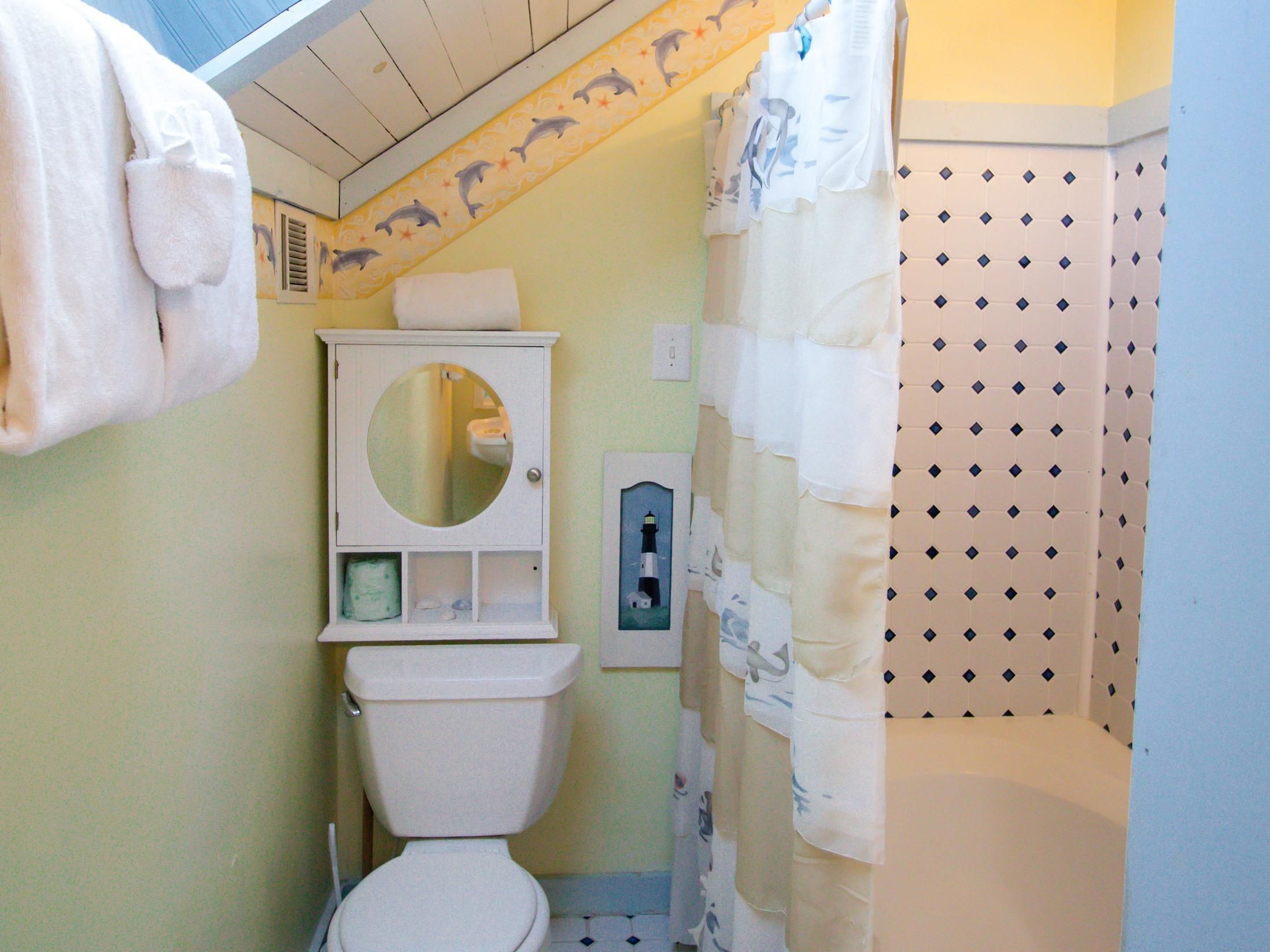 Une salle de bain équipée de toilettes, d’un miroir, d’un porte-serviettes et d’un rideau de douche.