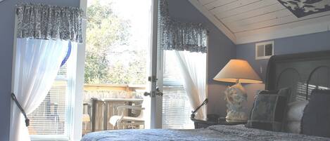 Une chambre à coucher avec un lit, une table de chevet, une lampe et une vue sur l’extérieur.