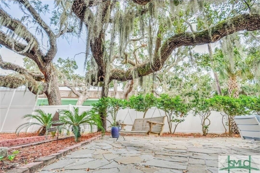 Un patio con una hamaca, un banco y una planta en maceta.
