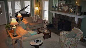Un salon chaleureux avec un piano, une cheminée et des fauteuils confortables.