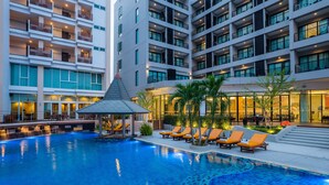 Zona de piscina hotelera de diseño moderno, que incluye una piscina con azulejos azules y una terraza con tumbonas.