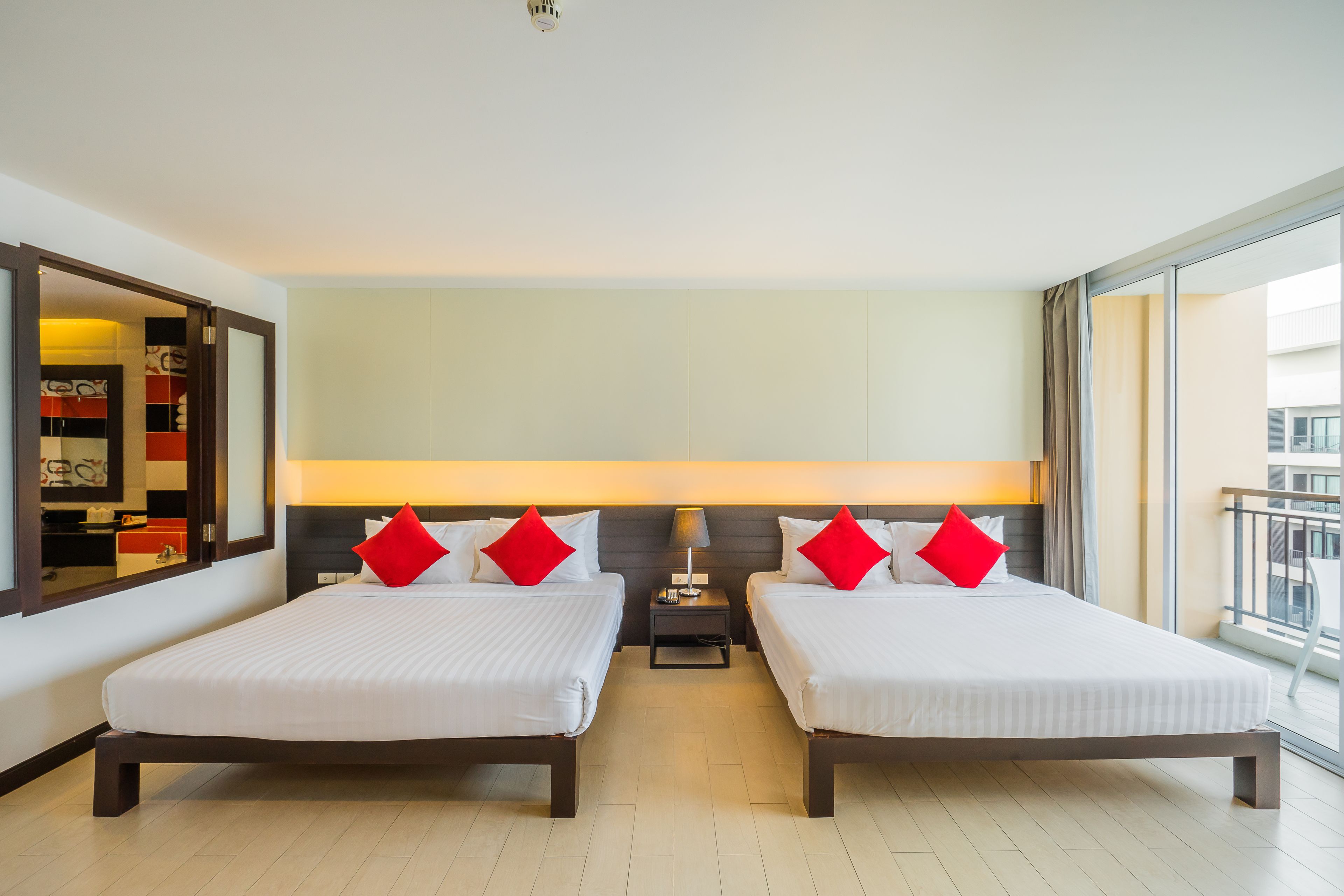Quarto de hotel com duas camas, uma mesa de cabeceira, uma janela grande e vista para a cidade.