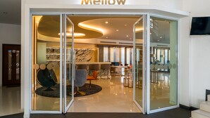 Un moderno vestíbulo de hotel con entrada de vidrio, mostrador de recepción y mobiliario contemporáneo.