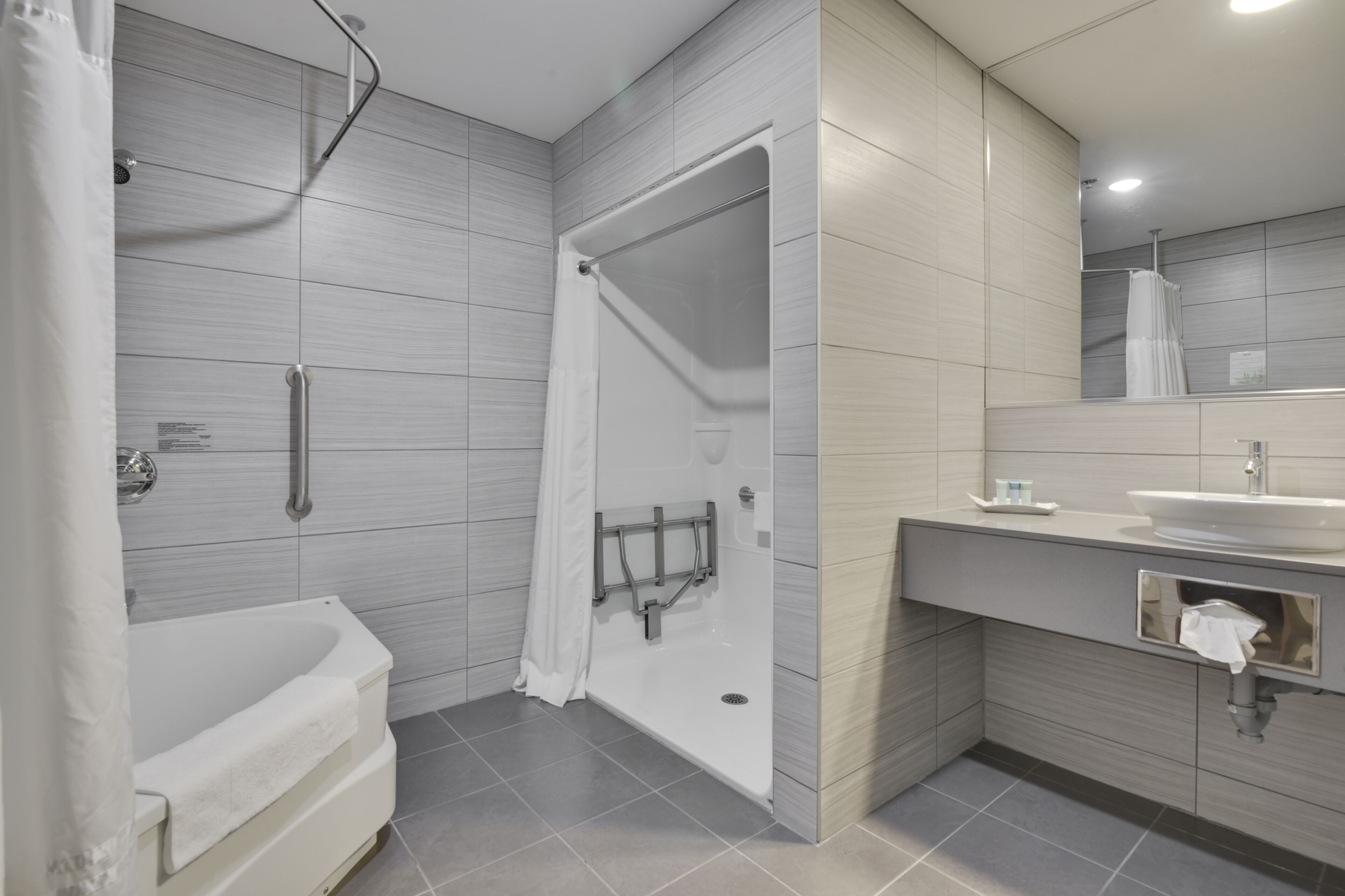 A modern bathroom with a walk-in shower, a bathtub, and a vanity with a sink and mirror.