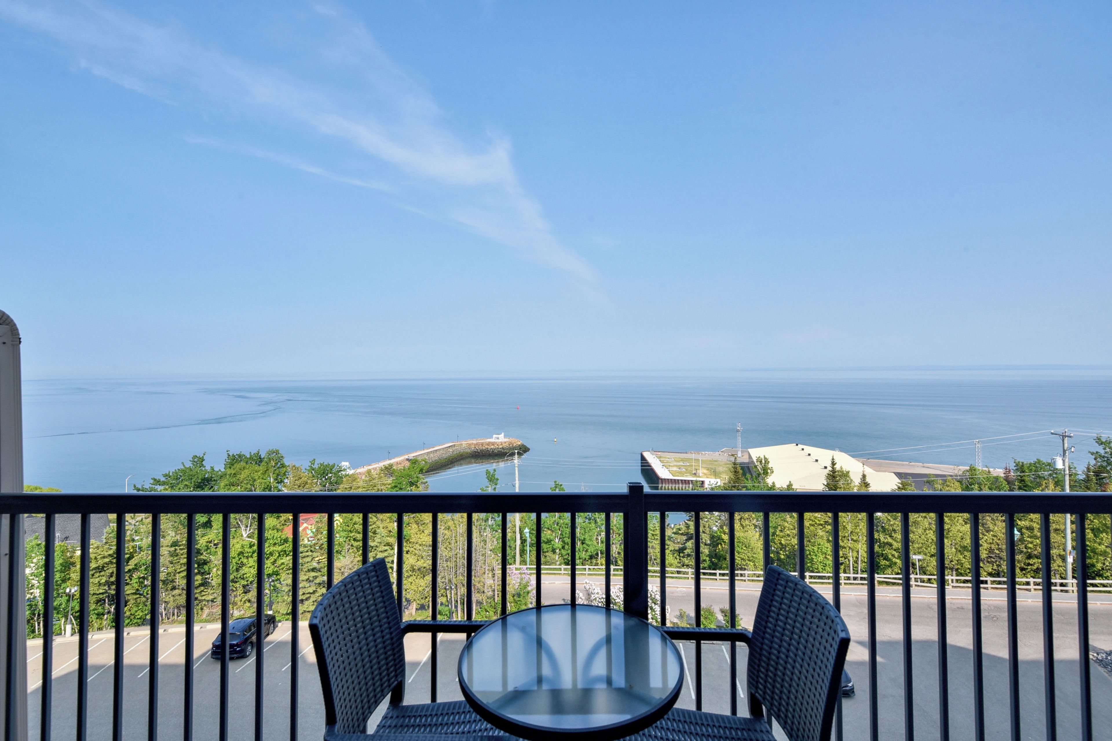 En balkon med et bord og stole, der ud til et vandområde og landskabet i det fjerne.