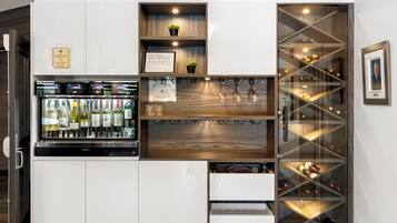 Un meuble de rangement pour vins doté de plusieurs étagères et de tiroirs, un compartiment réfrigéré contenant des bouteilles et un tableau encadré accroché au mur.
