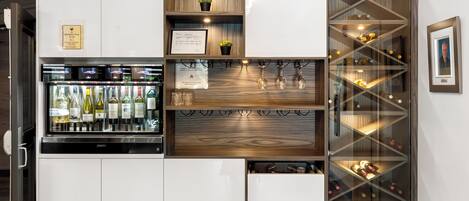 A wine storage unit with multiple shelves and drawers, a refrigerated section with bottles, and a framed picture on the wall.