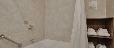 A bathroom with a bathtub, a shower, and a towel rack.