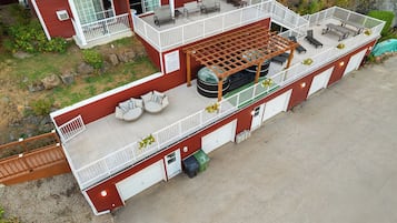 Un edificio de dos pisos con un patio cubierto, asientos al aire libre y un jacuzzi.