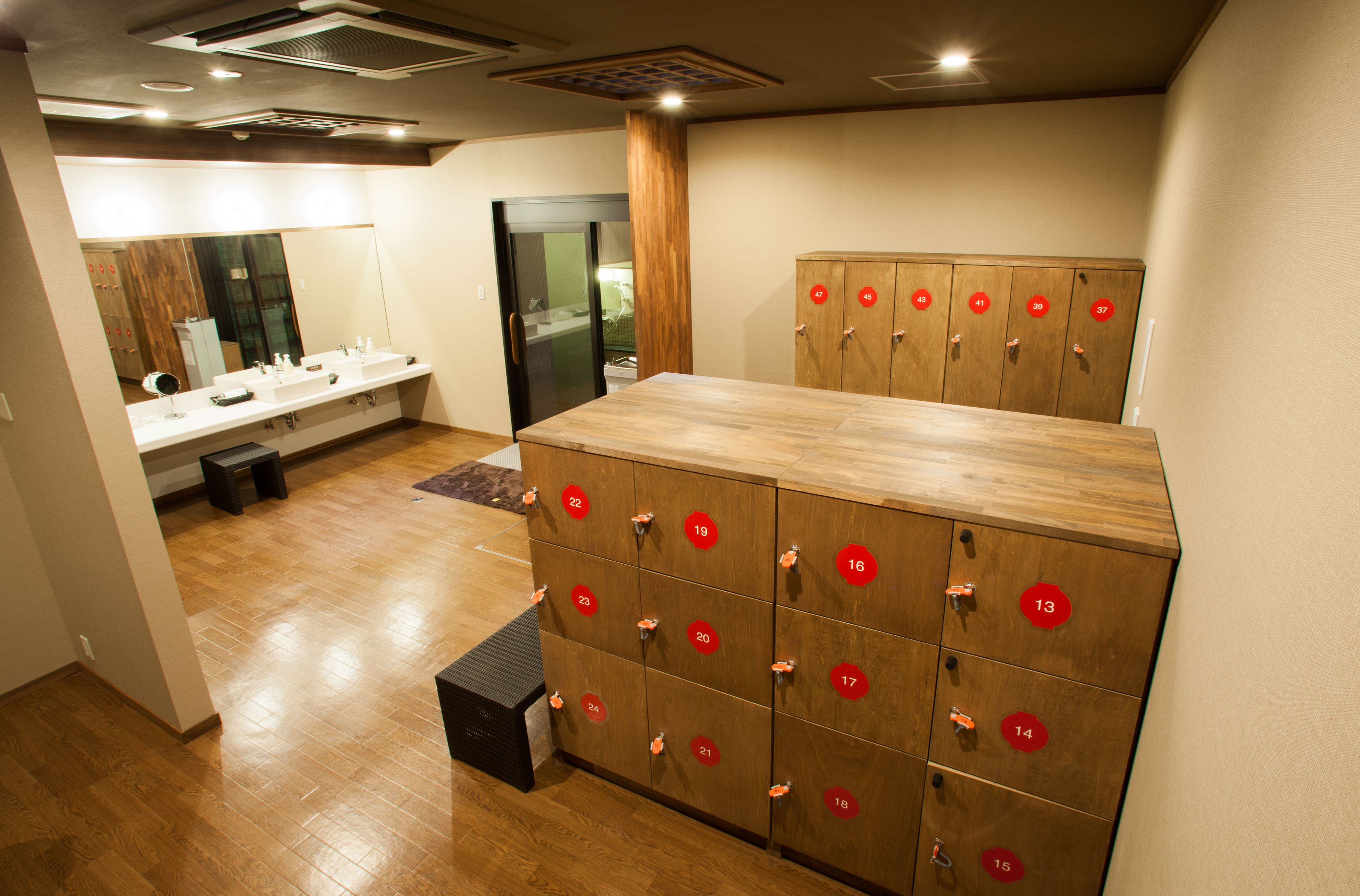 A hotel bathroom with wooden lockers, a mirror, and a sink.
