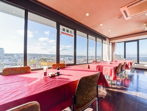 Een vergaderruimte met grote ramen en uitzicht over de stad, ingericht met tafels en stoelen.