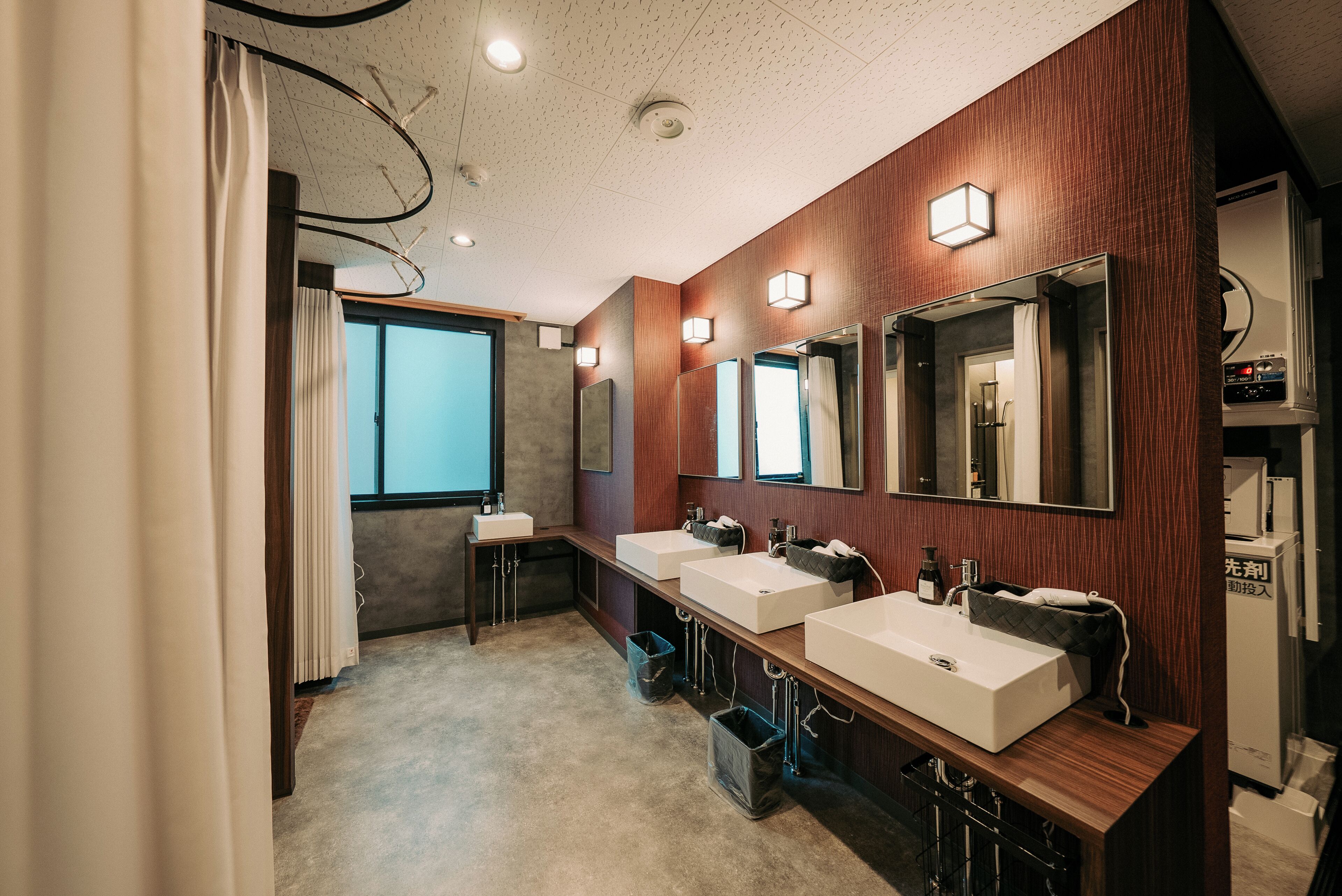 Une salle de bain moderne avec trois lavabos, un lambris en bois et des miroirs.