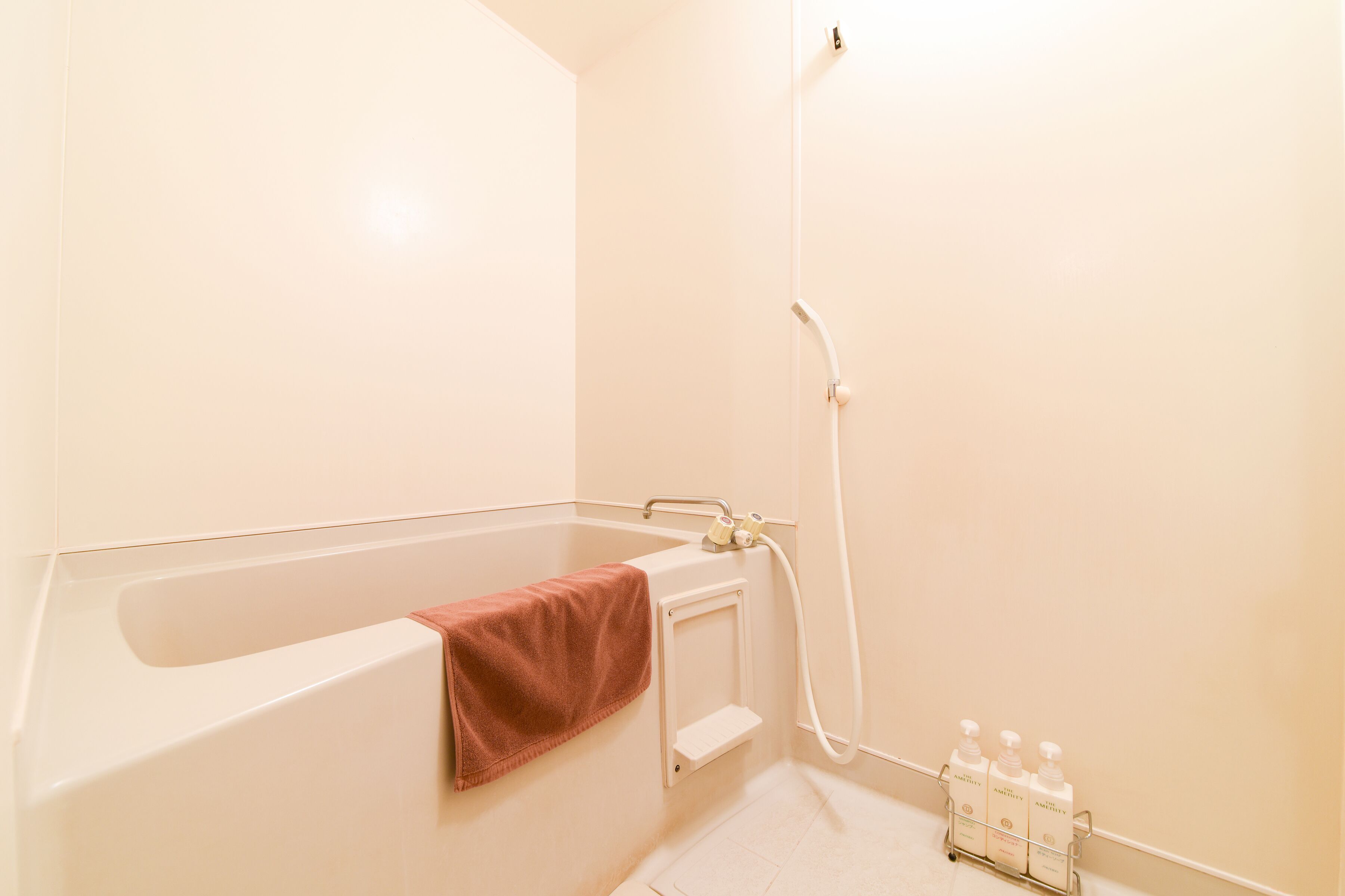 A bathroom with a bathtub, a towel rack, and a shelf with toiletries.