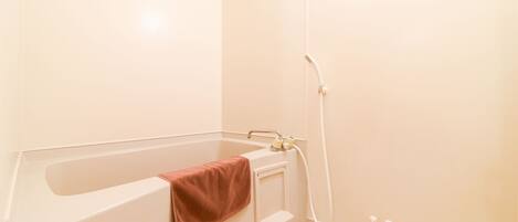 A bathroom with a bathtub, a towel rack, and a shelf with toiletries.