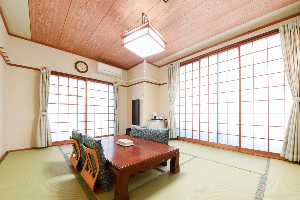 Une pièce de style japonais traditionnel, avec un sol recouvert de tatamis, une table en bois et des paravents en papier.