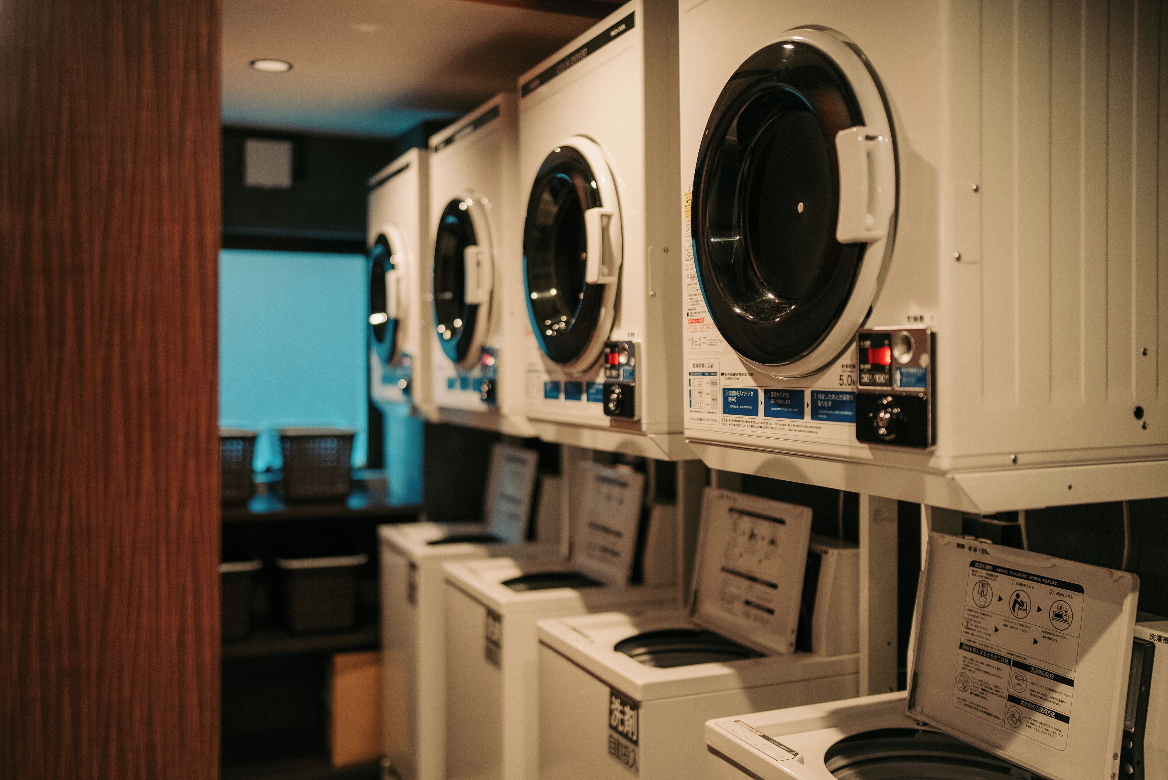 A row of front-loading washing machines in a commercial setting.