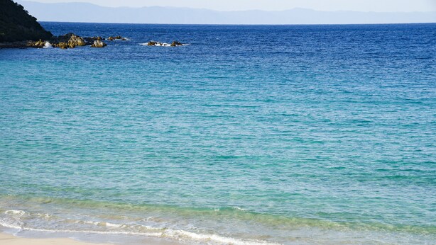 Una playa con agua turquesa cristalina y una orilla arenosa.