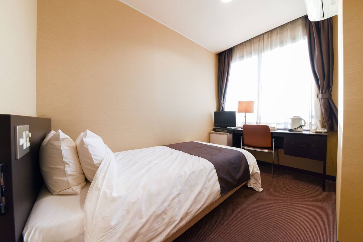 Une chambre d’hôtel équipée d’un lit, d’un bureau, d’une chaise, d’une lampe et d’un téléviseur.