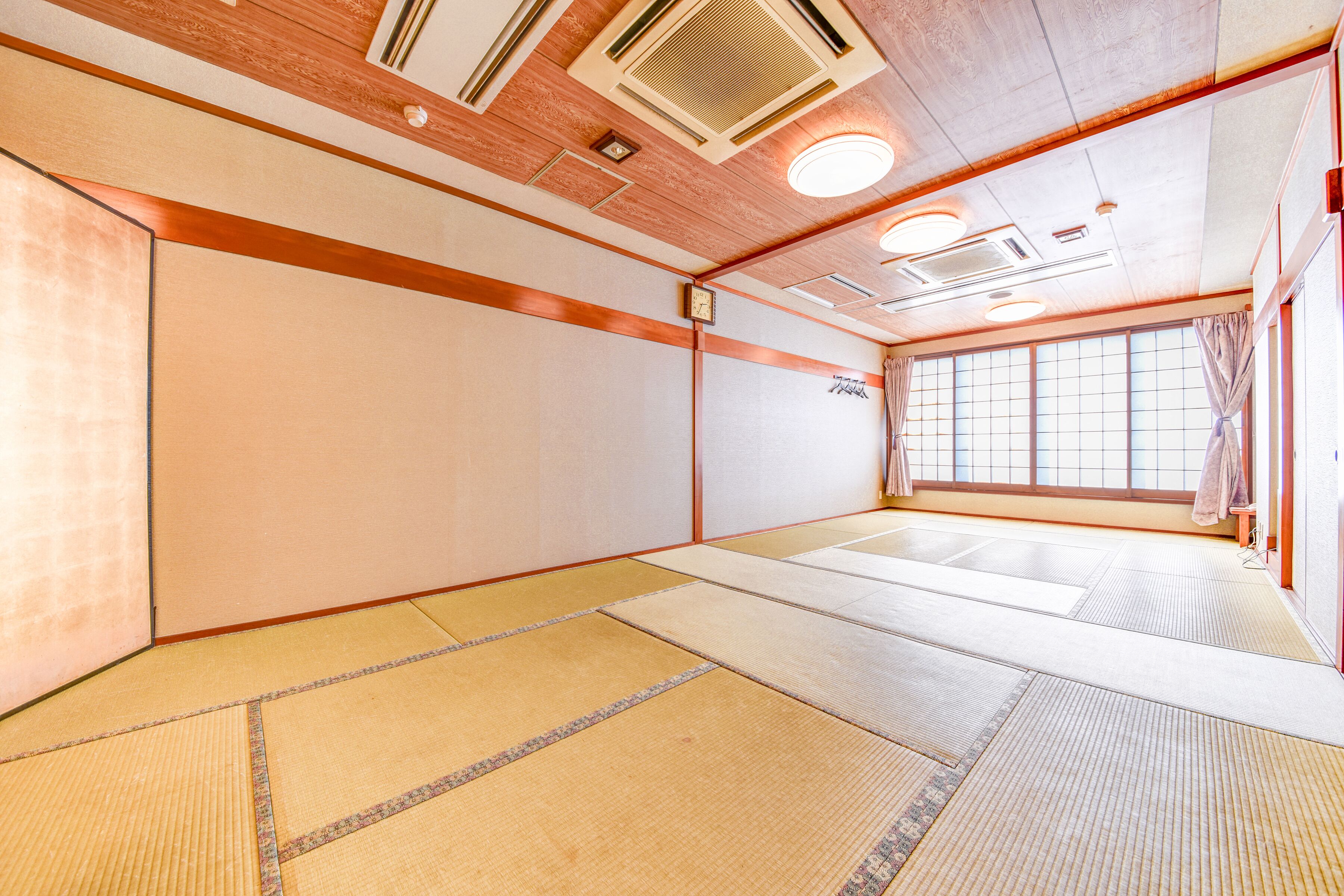 A traditional tatami mat room with wooden beams, a shoji screen, and a shoji door.
