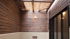 Un jacuzzi con techo y paredes de madera, una ventana de vidrio a la derecha y un panel de control en el centro.