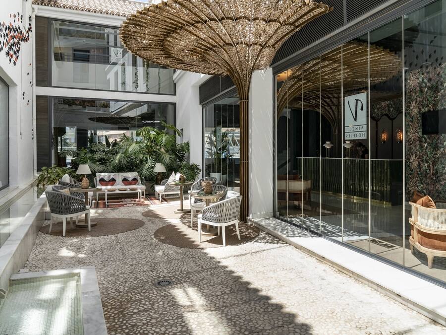 Recepció d'hotel moderna amb zona de seients, un parasol gran i vista cap a l'interior.