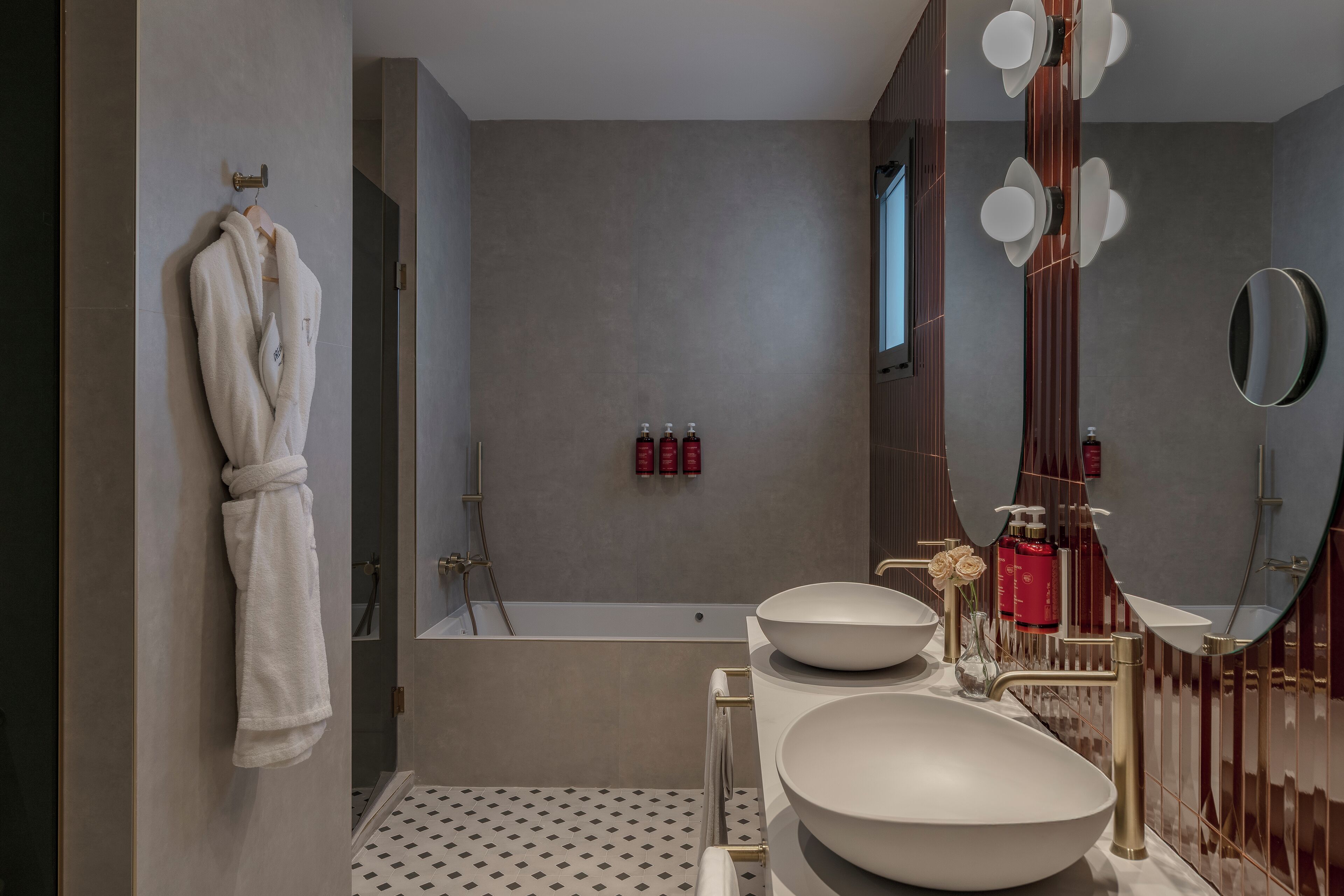 Un baño moderno con una bañera grande, dos lavamanos y un espejo.