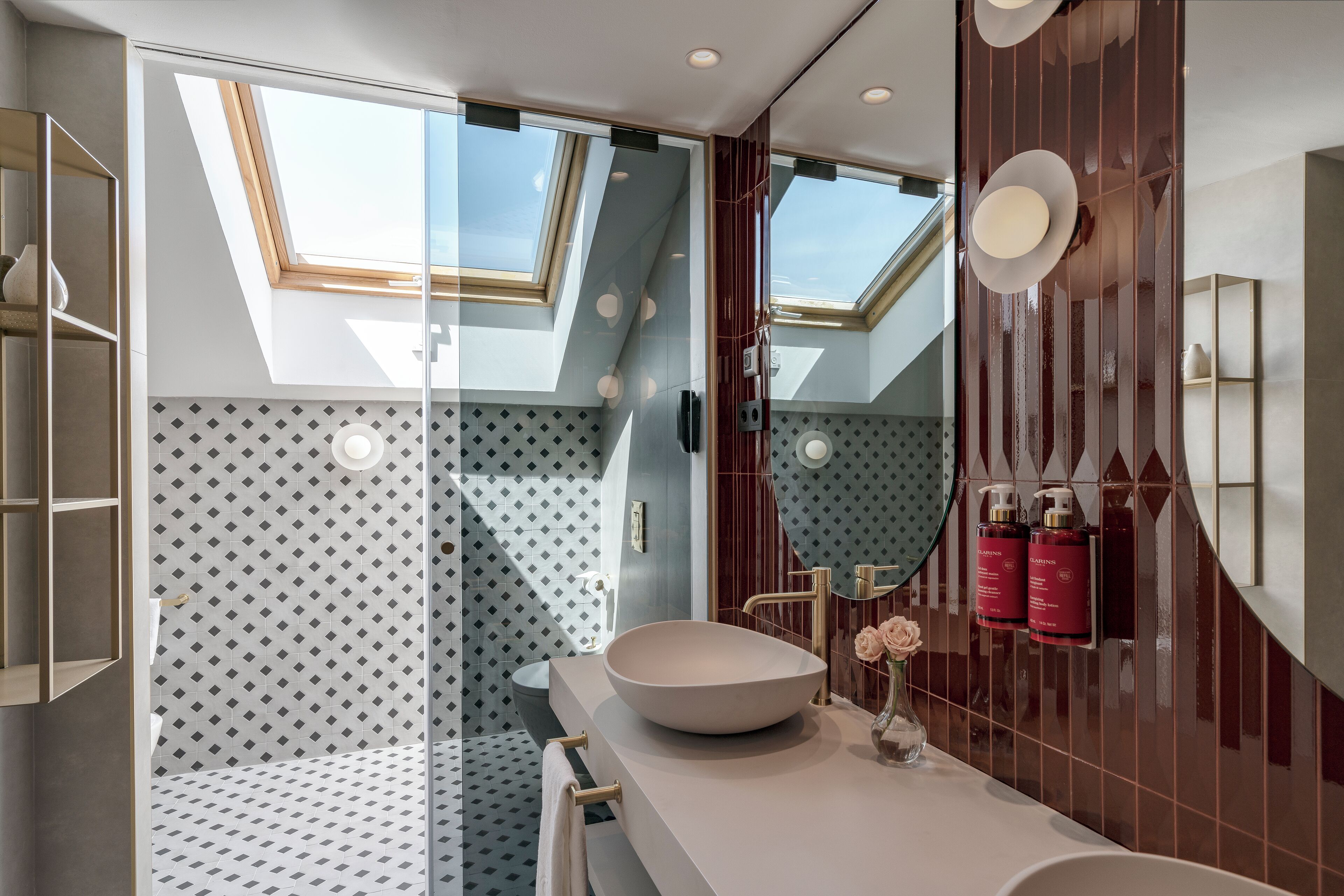 A modern bathroom with a skylight, a large mirror, and a vessel sink.