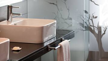 Un baño moderno con un lavabo rectangular, un espejo y una cabina de ducha de vidrio.