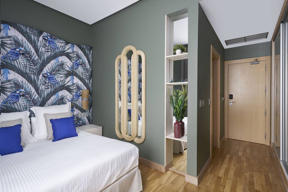 A bedroom with a bed, a large mirror, a wardrobe, and a plant.