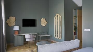 Un dormitorio moderno con cama, escritorio, silla, televisor y espejo.