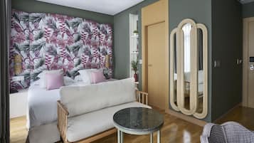 A bedroom with a bed, a sofa, a round table, a mirror, and a wardrobe.